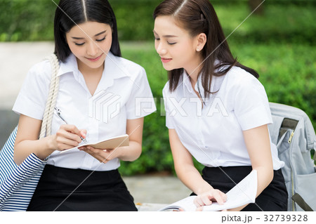 a girl is pointing something in notebook to her friend 32739328