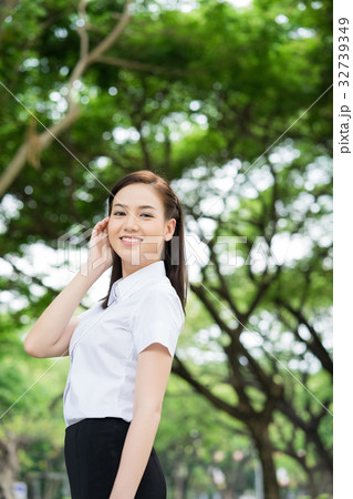 A beautiful student is smiling and standing in the park A beautiful student is smiling and standing in the park 32739349