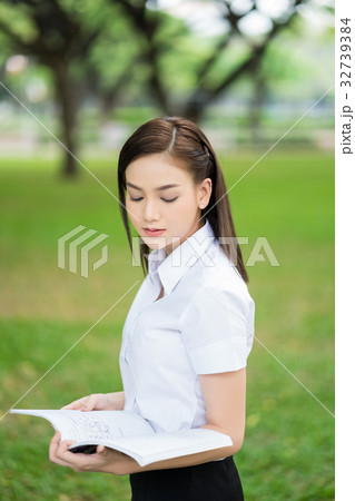 The portrait of schoolgirl looking at the book outdoors 32739384