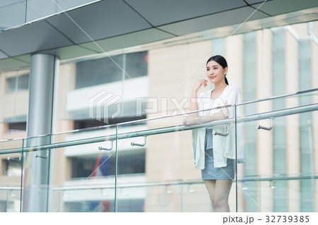The lady is standing on balcony and putting right hand near her chin 32739385