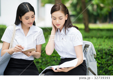 The portrait of two girls sitting outdoors and dicussing together 32739393