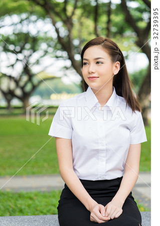a portrait of a schoolgirl sitting on the bench and looking 32739395