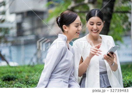 a picture of two women chatting and using the phone outdoors a picture of two women chatting and using the phone outdoors 32739483