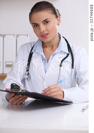 Doctor woman filling up medical form while  sittin 32746688