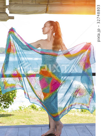 The young woman in a bright scarf pareo stand on a 32748803