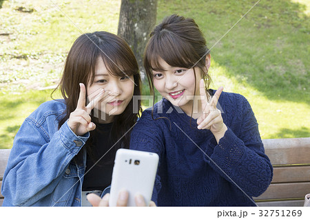 スマホで写真を撮る仲良し女子大生の写真素材
