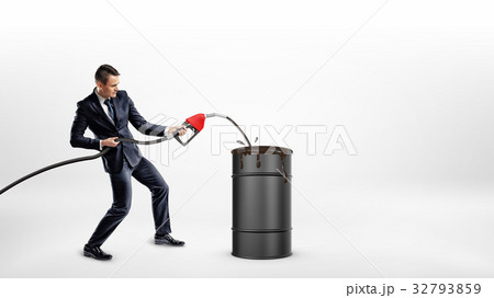 A businessman holds a gas nozzle and overfills a 32793859