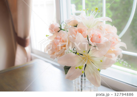 Flowers in a Glass Vase on table near window. 32794886