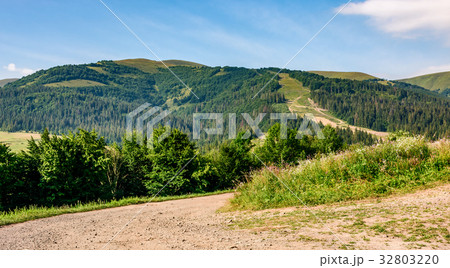 countryside road through meadow to mountains countryside road through meadow to mountains 32803220