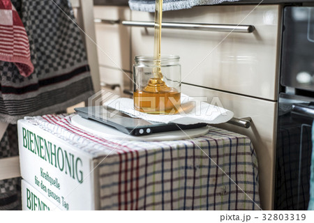 Beekeeper filling up fresh golden honey into glass 32803319