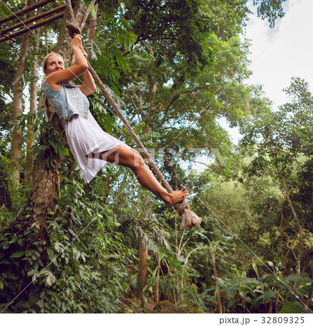 Woman on rope swing on wild jungle background 32809325
