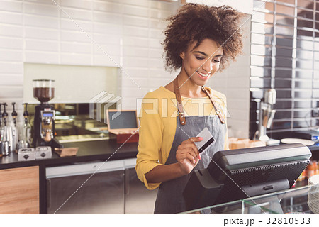 Cheerful young woman cashier is working in cafe Cheerful young woman cashier is working in cafe 32810533