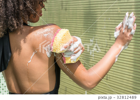 Serious youthful african woman washing in shower 32812489