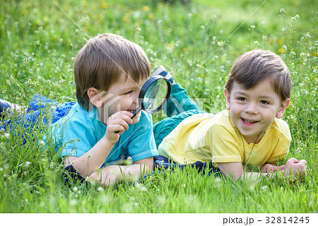 Two boys brothers with magnifying glass outdoors. Two boys brothers with magnifying glass outdoors. 32814245