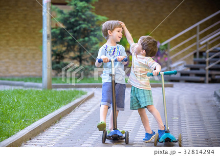 Two cute boys, compete in riding scooters, outdoor Two cute boys, compete in riding scooters, outdoor 32814294
