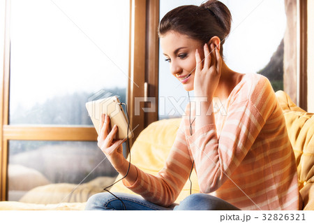 Woman sitting in the living room and listen to music Woman sitting in the living room and listen to music 32826321