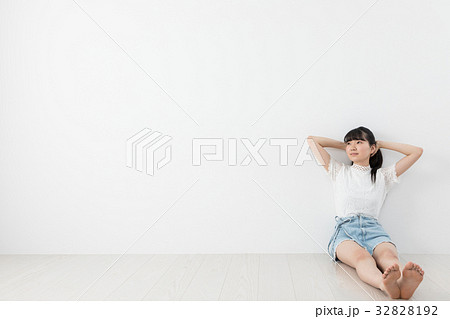 壁に寄り掛かる若い女性 の写真素材