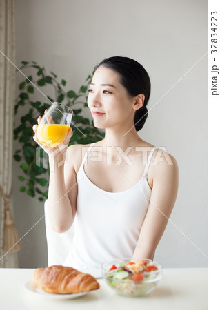 オレンジジュースを飲む女性 朝食の写真素材