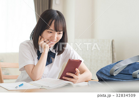 勉強中スマホを見る女子高生の写真素材