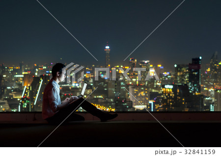 Asian businessman sitting and using the laptop over the cityscape background at night time, Business success and technology concept Asian businessman sitting and using the laptop over the cityscape background at night time, Business success and technology concept 32841159