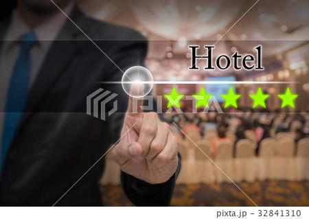Businessman pointing five star button to increase rating of hotel over Abstract blurred photo of conference hall or seminar room with attendee background, business evaluation concept, Increase rating 32841310