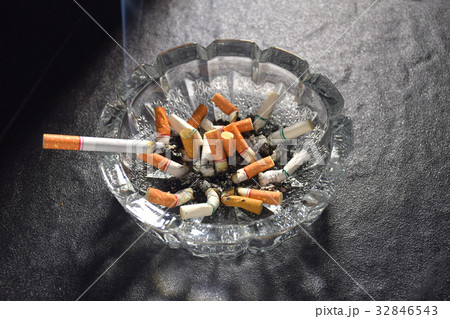 Lit cigarette with smoke lying on an ashtray 32846543