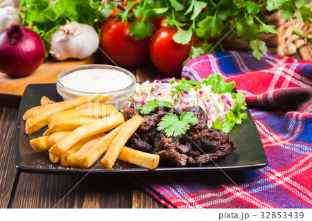 Kebab of beef with french fries and salad Kebab of beef with french fries and salad 32853439