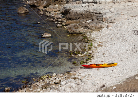 Orange kayak on pebbly beach of sea coast 32853727