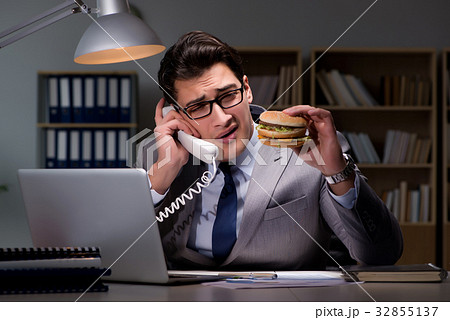 Businessman late at night eating a burger 32855137
