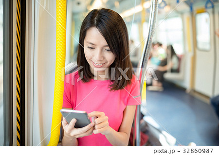 Young woman looking at cellphone inside train compartment Young woman looking at cellphone inside train compartment 32860987