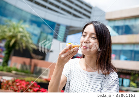Woman enjoy egg tart at outdoor 32861163