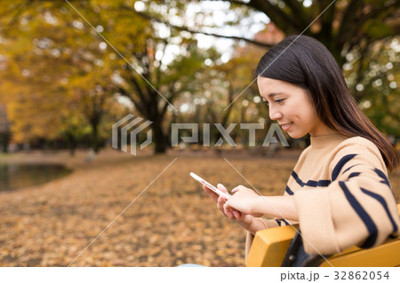 Woman using cellphone at park Woman using cellphone at park 32862054