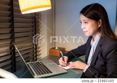 Businesswoman writing on the note with laptop computer Businesswoman writing on the note with laptop computer 32862105