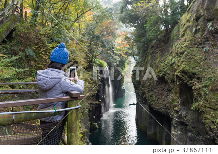 Woman using cellphone to taking photo in Takachiho Gorge 32862111