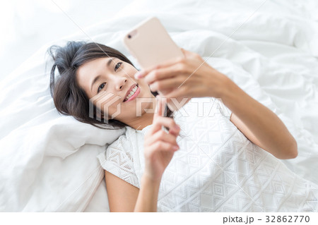 Woman using mobile phone and lay down on bed Woman using mobile phone and lay down on bed 32862770