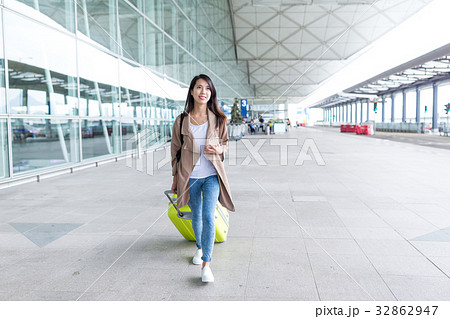 Woman walking with luggage in airport Woman walking with luggage in airport 32862947