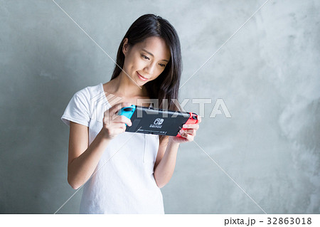 Hong Kong, 19 May 2017 -:Woman playing game on Nintendo Switch over gray background Hong Kong, 19 May 2017 -:Woman playing game on Nintendo Switch over gray background 32863018