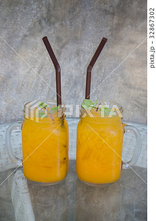 Orange juice with ice cube on glass table Orange juice with ice cube on glass table 32867302