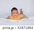 Asian infant lie on the stomach, in orange shirt 32871864