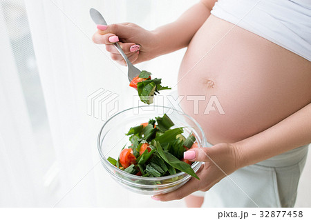 Pregnant woman starts to eat fresh salad 32877458
