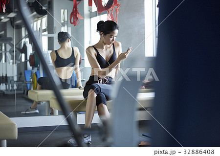 The girl is sitting and looking at the phone in sport club. 32886408