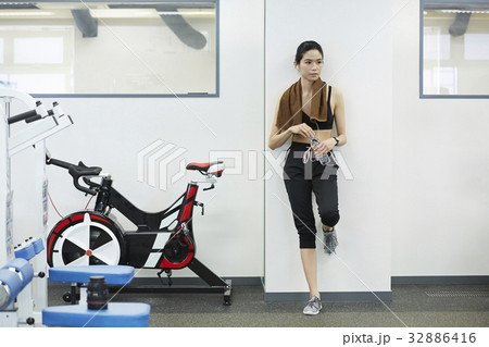 The woman is holding the water bottle and looking at something. 32886416