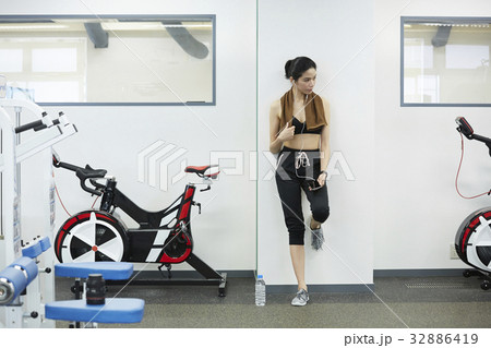 The girl is standing and looking at something in fitness club. 32886419