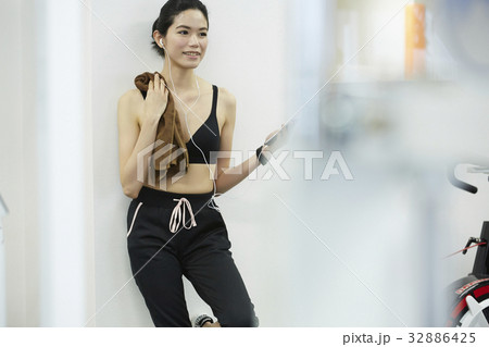 The woman with sportswear is standing and smiling. The woman with sportswear is standing and smiling. 32886425