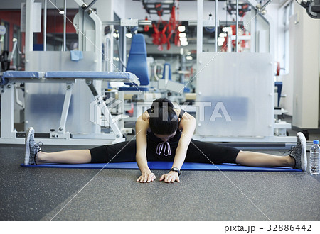 A trainee is stretching alone at a fitness club A trainee is stretching alone at a fitness club 32886442