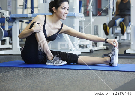 A woman is sitting and warming up at a fitness room 32886449