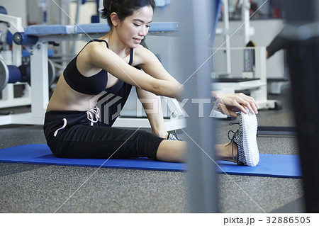 the woman is sitting on a mat and holding her right foot 32886505