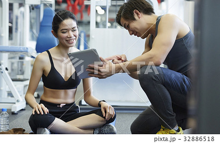 the man is pointing something on tablet for the happy girl sitting the man is pointing something on tablet for the happy girl sitting 32886518
