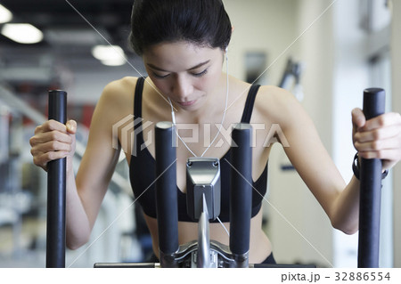 a woman is training on exercise machine in modern gym club a woman is training on exercise machine in modern gym club 32886554