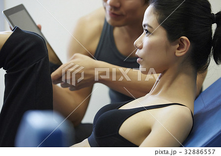 a woman is exercising while a man is using tablet in fitness club a woman is exercising while a man is using tablet in fitness club 32886557
